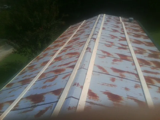 Rusted metal roof panels with new wood purlins before replacement — Storm Damage Roof Repair in Stockbridge by Roofing Brothers