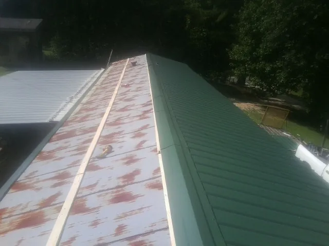 Old rusted panels beside newly installed green metal roofing — Wind Damage Roof Repair by Roofing Brothers in Stockbridge