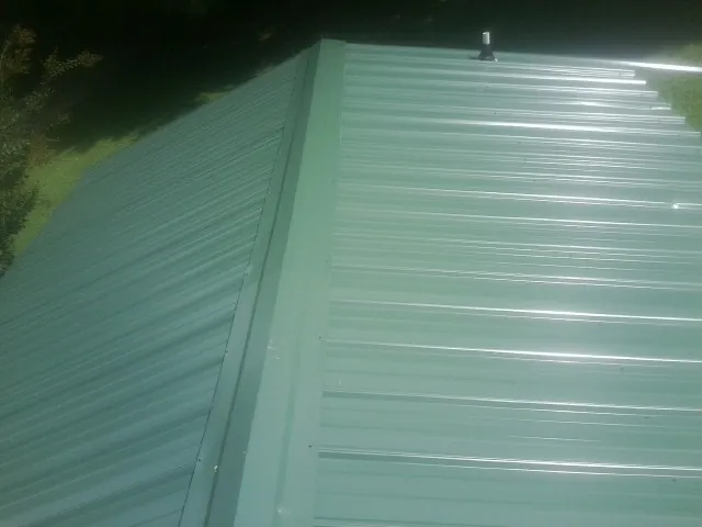 New green metal panels meeting at the ridge of a roof — Flat Roof Repair work by our crew in Stockbridge