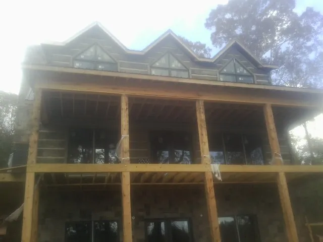 Dormers and porch framing on a large log home under construction — Roof Coating work by our crew in Stockbridge