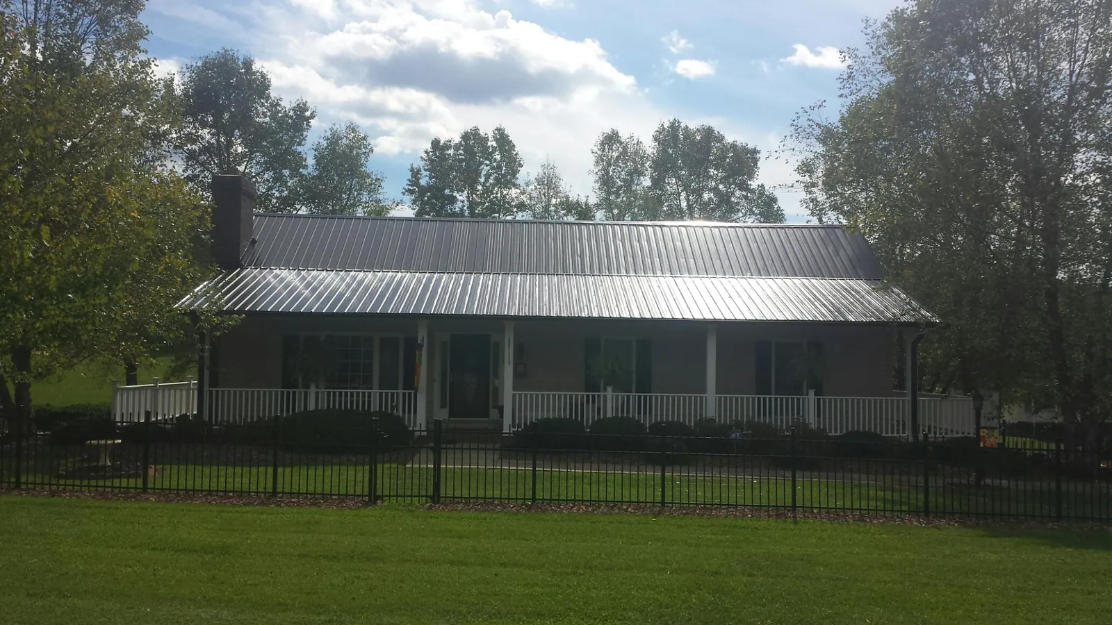 Gray metal roof on a brick ranch with a full width front porch — Gutter Guard Installation work by our crew in Stockbridge